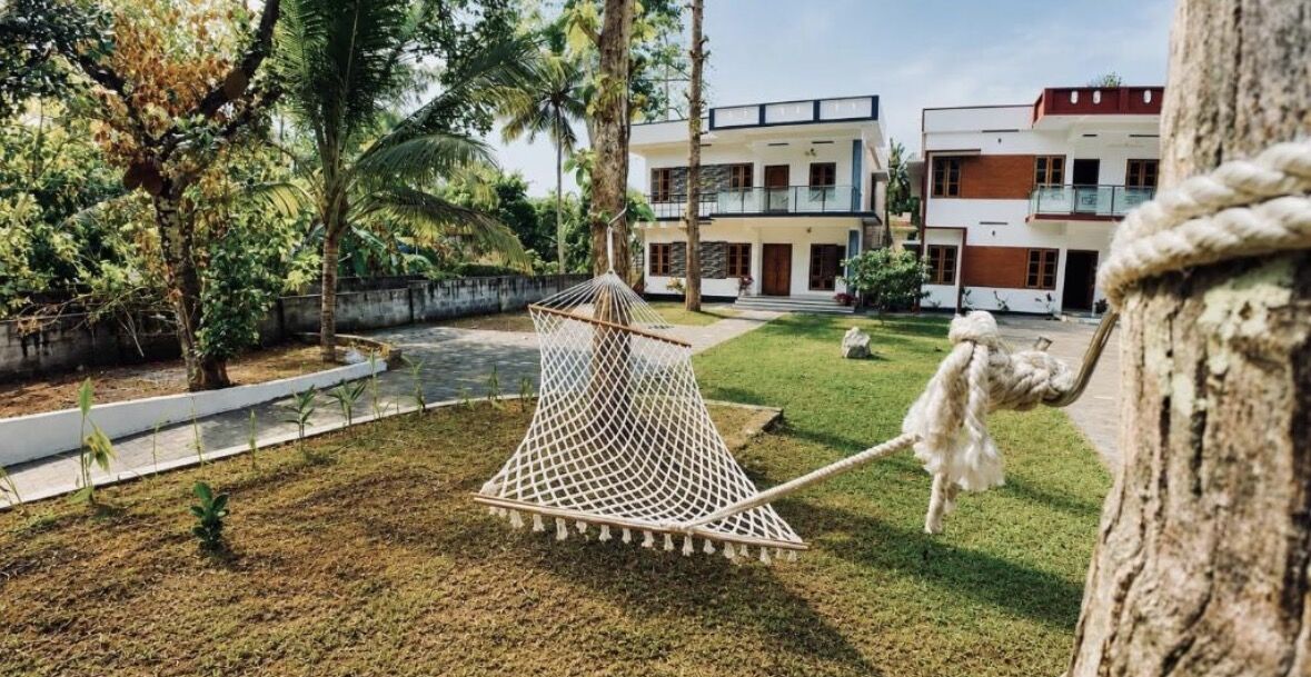 A rope hammock on the lawn between the two white ZENWAYS houses