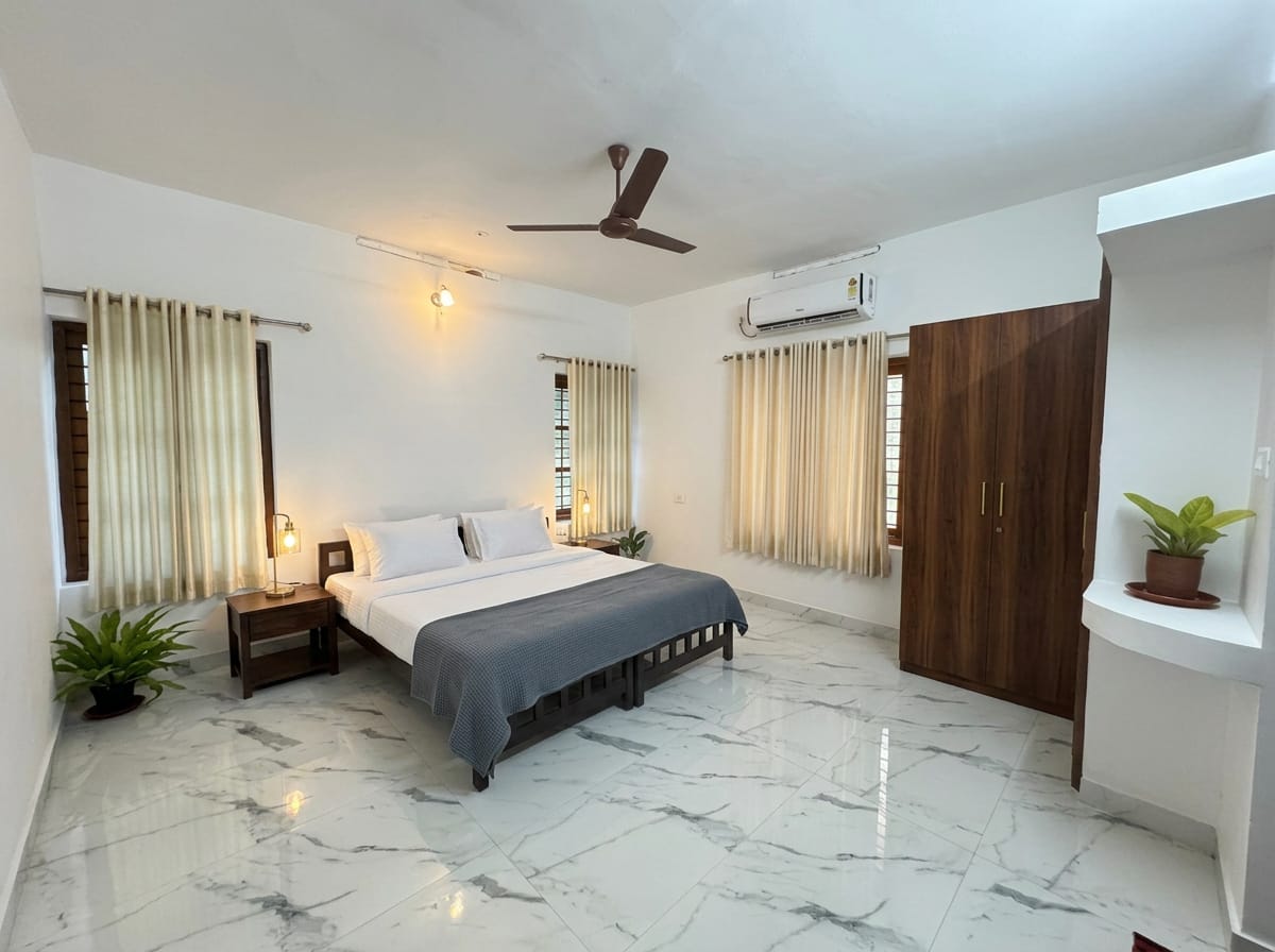 Comfort Room I — twin beds with white linen, a shared bedside table and lamp, wardrobe and marble floor